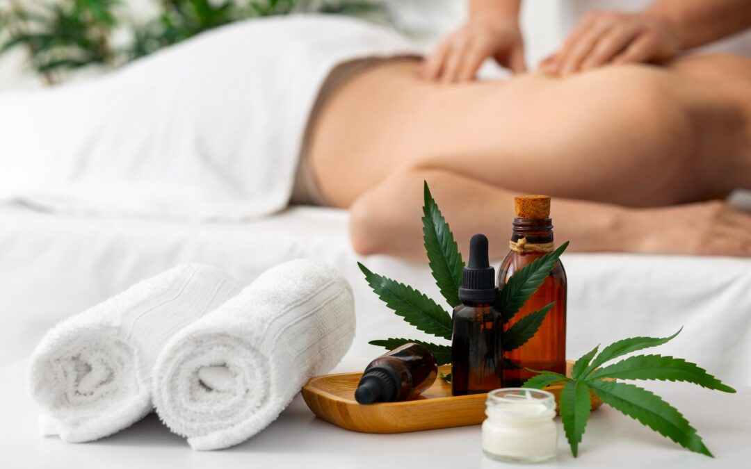 Person receiving relaxing massage with CBD and essential oils, fresh cannabis leaves, towels, and bottles on tray for adrenal fatigue recovery.