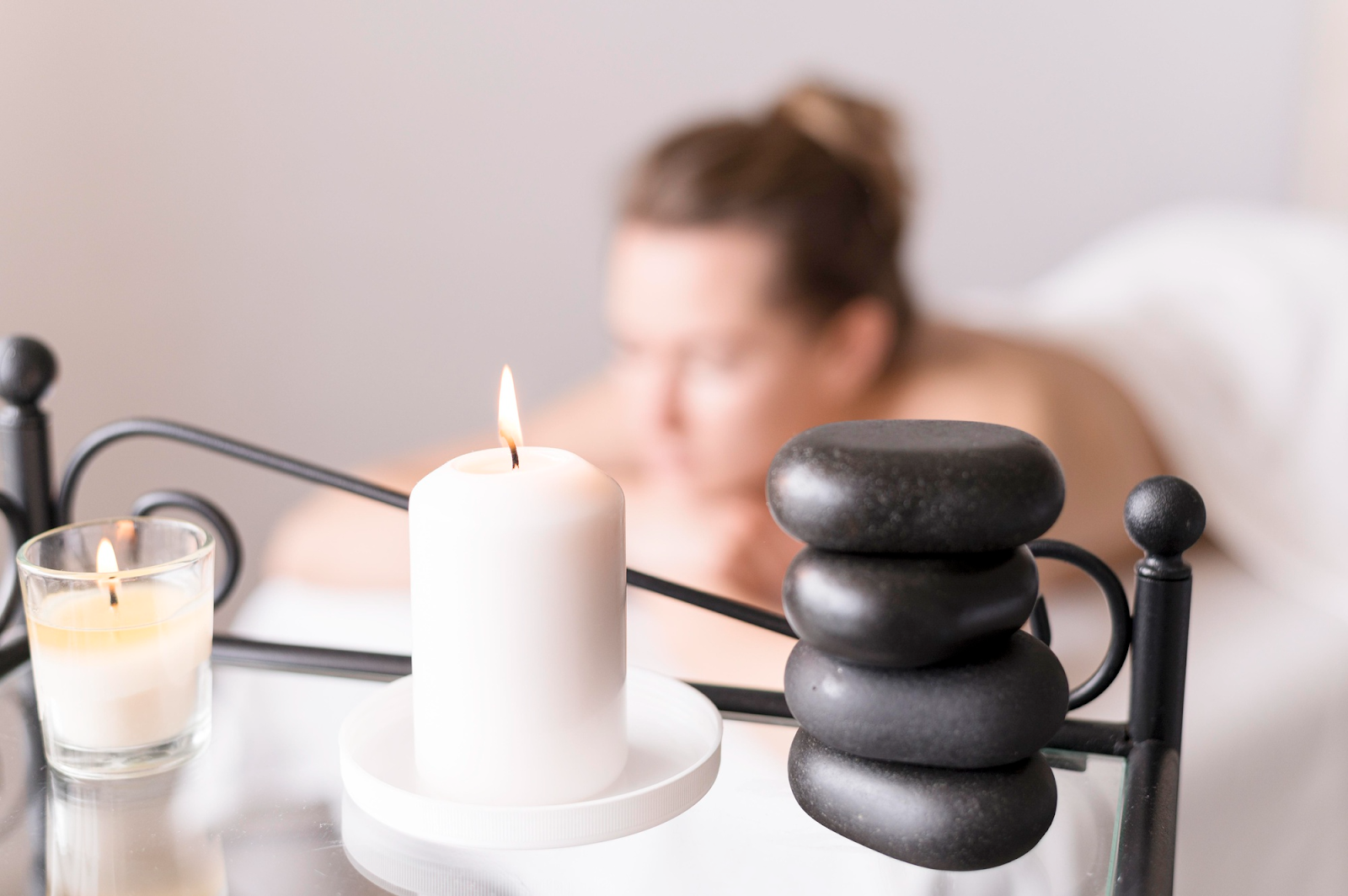 Woman lying on a massage table while warm stones and aromatherapy oils enhance relaxation.