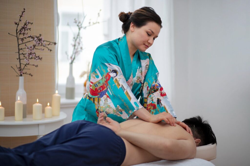 Therapist in a kimono performing deep tissue work on a client's back, a contrast to Thai massage. 
