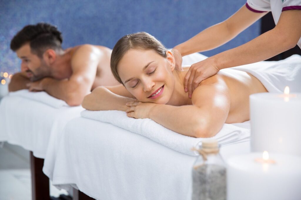 Happy couple enjoying a relaxing, candlelit couples massage, highlighting a bonding experience. 