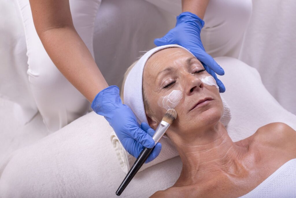 Older woman receiving a professional facial mask treatment, demonstrating San Diego anti-aging skincare.